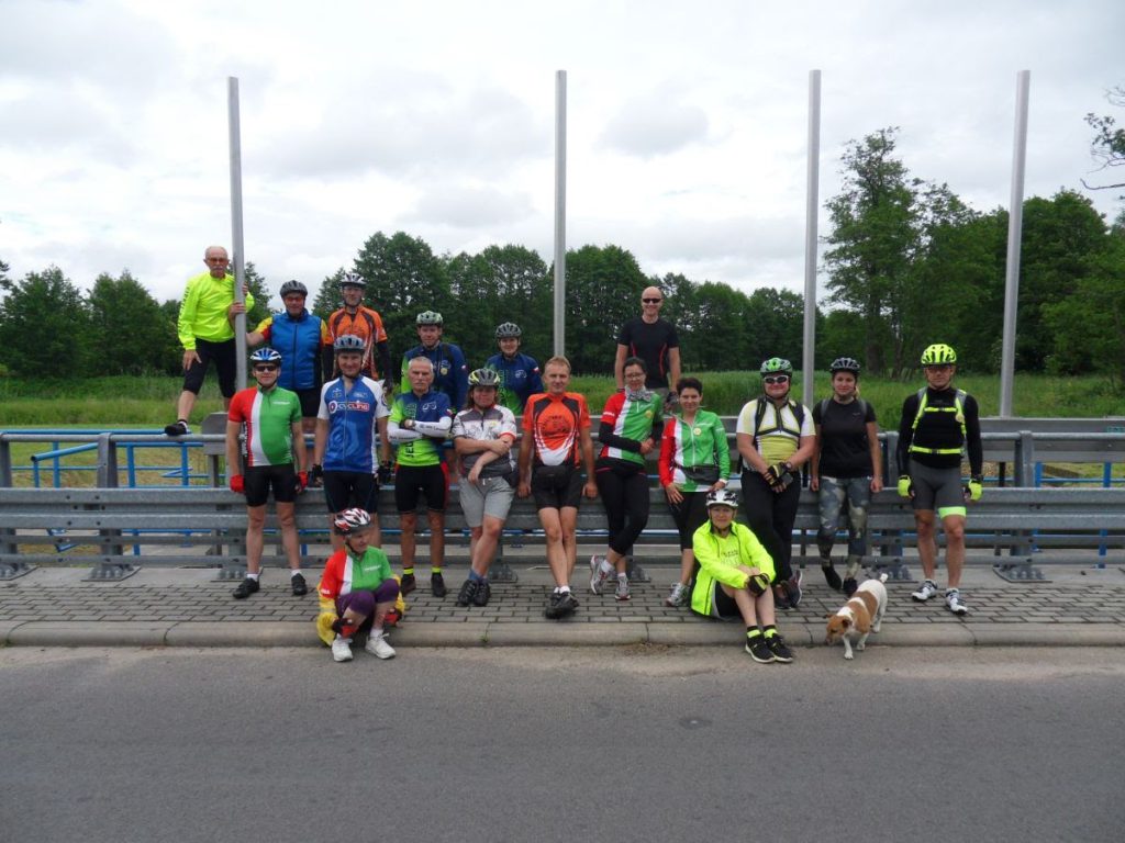 Grupa rowerzystów w koszulkach rowerowych pozuje do zdjęcia