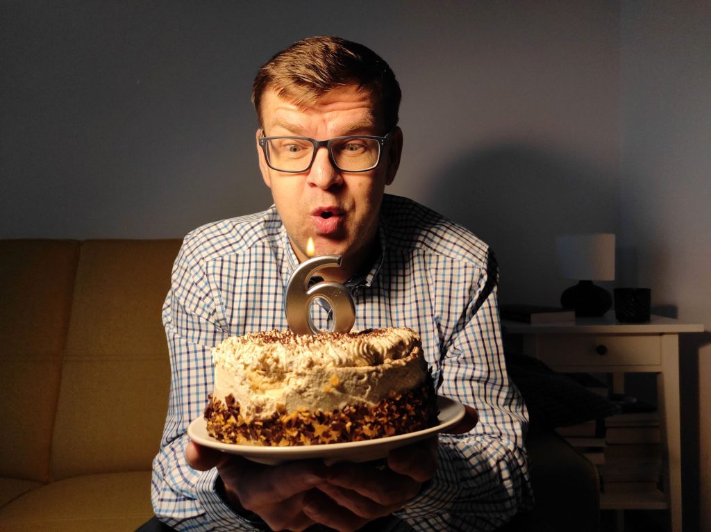 Rafał zdmuchuje świeczkę w kształcie cyfry 6 z tortu